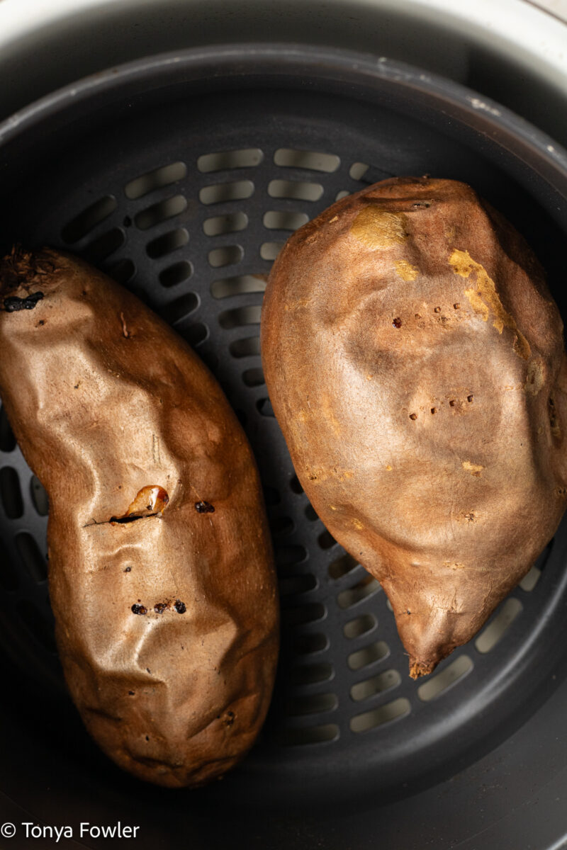 Overhead view of cooked baked sweet potatoes in an air fryer basket.