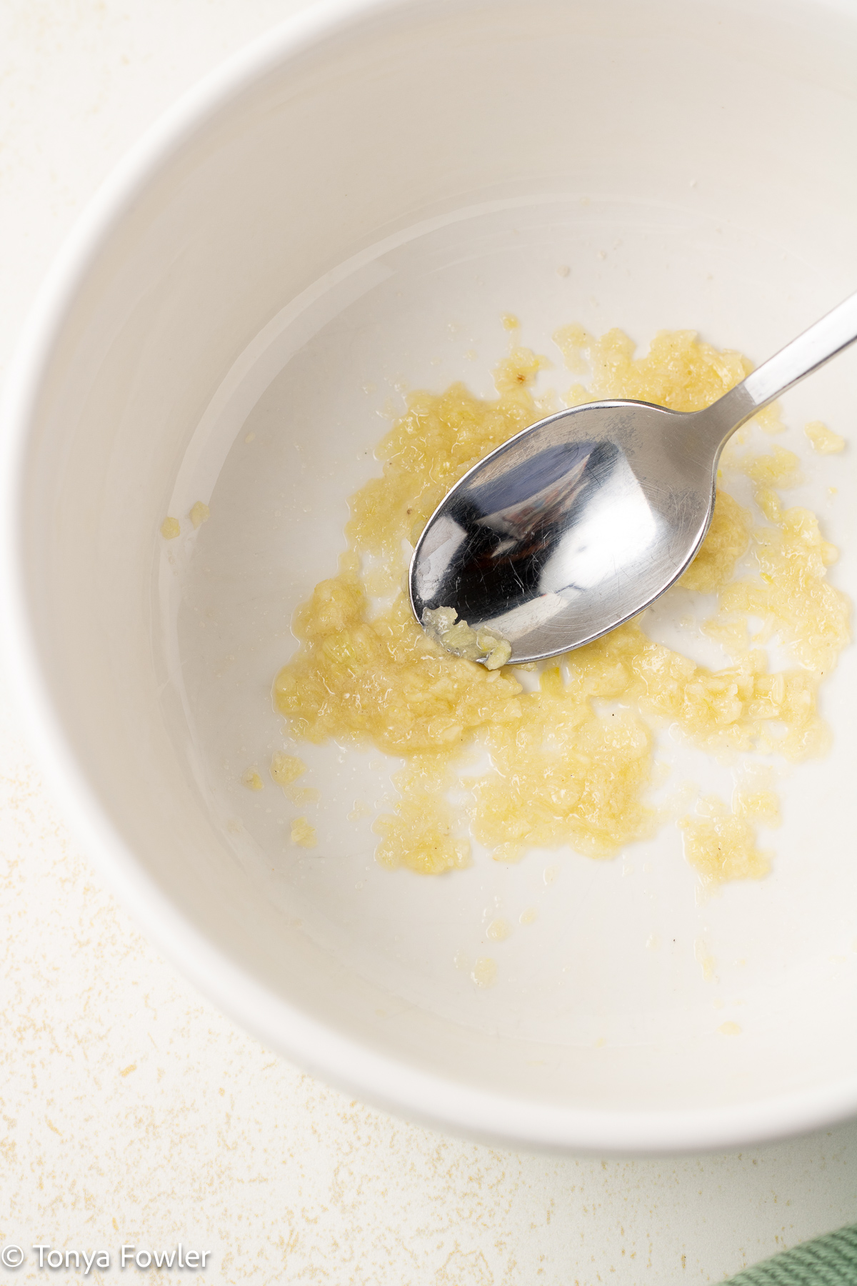 Minced garlic in a bowl with spoon.