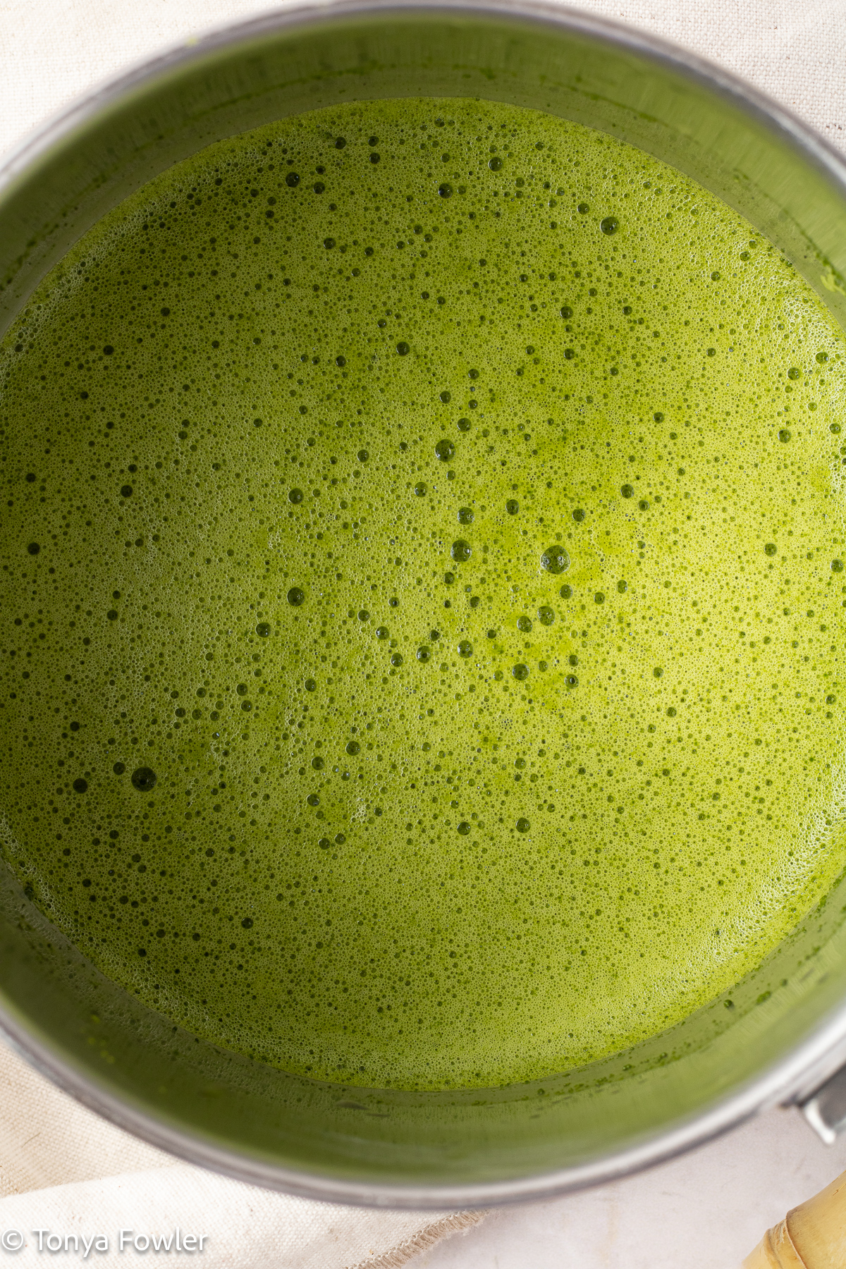Matcha powder whisked with water until frothy in a pot.
