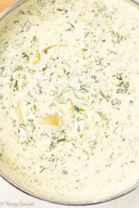 Spinach artichoke alfredo sauce in a skillet.