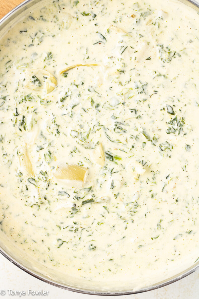 Spinach artichoke alfredo sauce in a skillet.