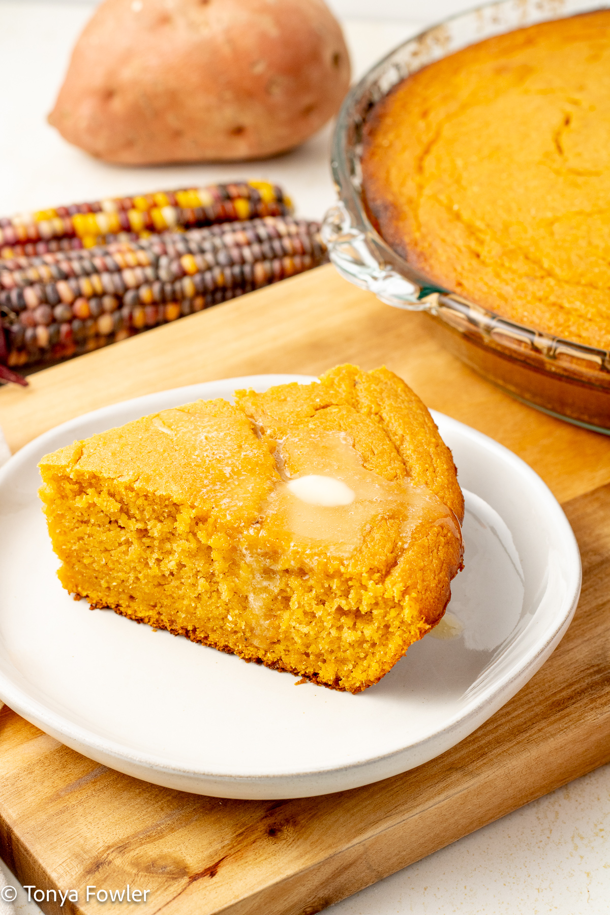 3/4 view of a slice of cornbread on a plate. 