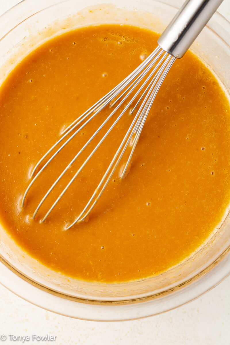 Sweet potato, eggs and milk whisked together in a bowl with a whisk. 