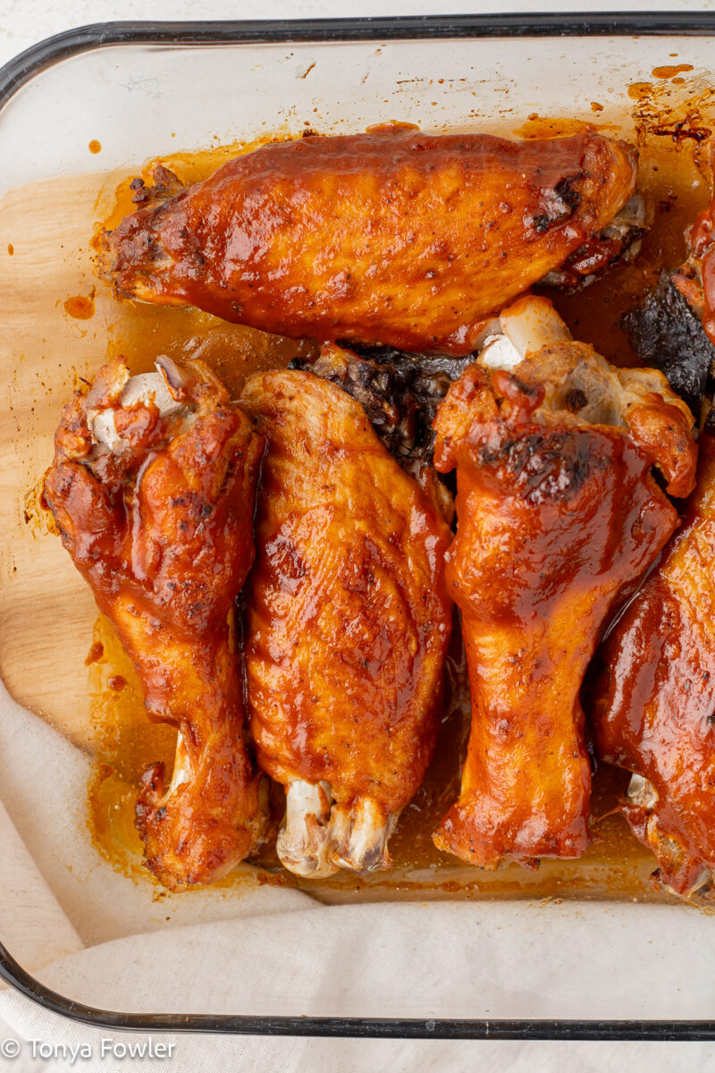 Turkey wings in a baking dish brushed with bbq sauce.