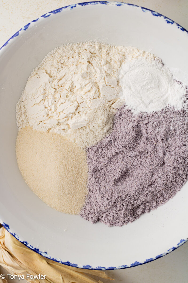 Blue corn meal, flour, and sugar in a bowl. 