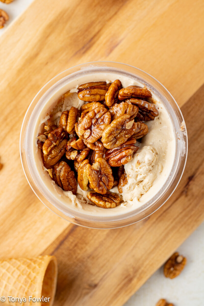 Overhead view of ice cream topped with butter pecans.