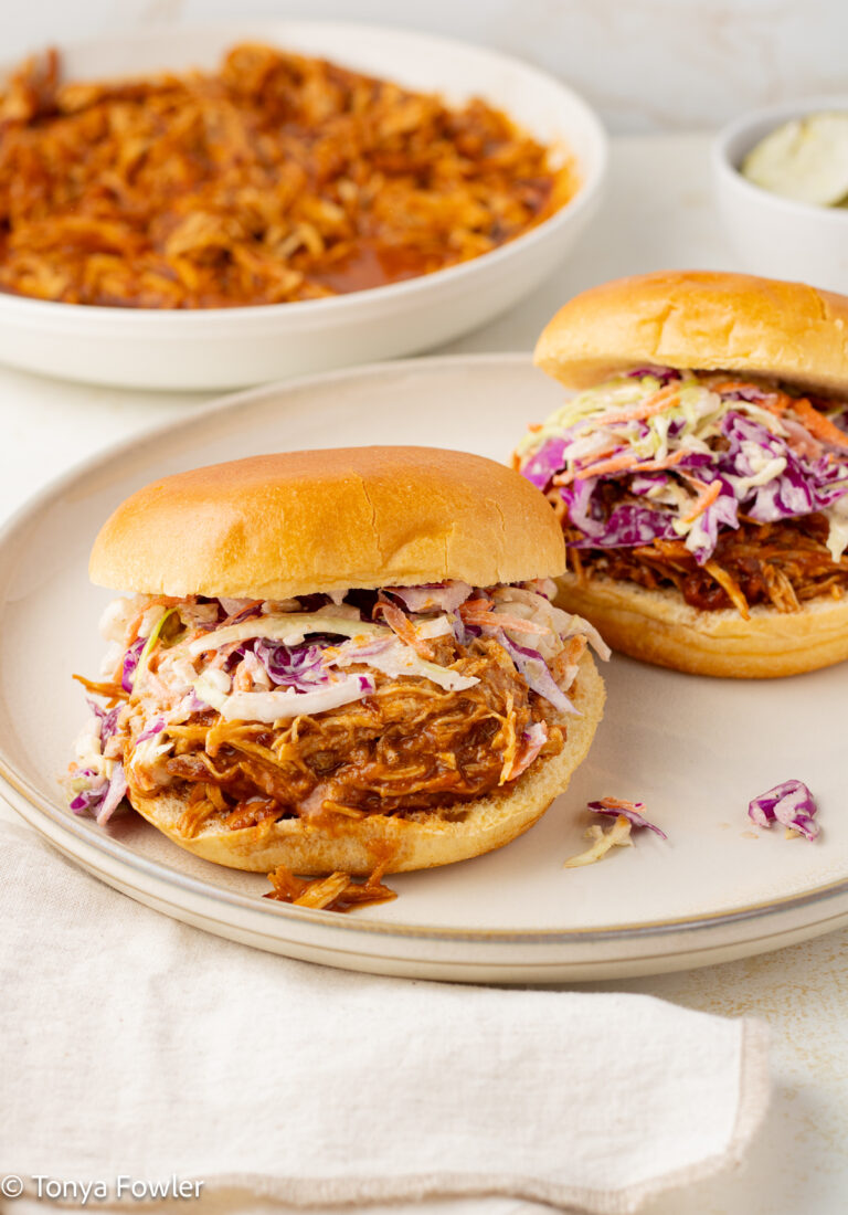 3/4 view of BBQ Pulled Turkey Sandwiches with coleslaw on a plate.