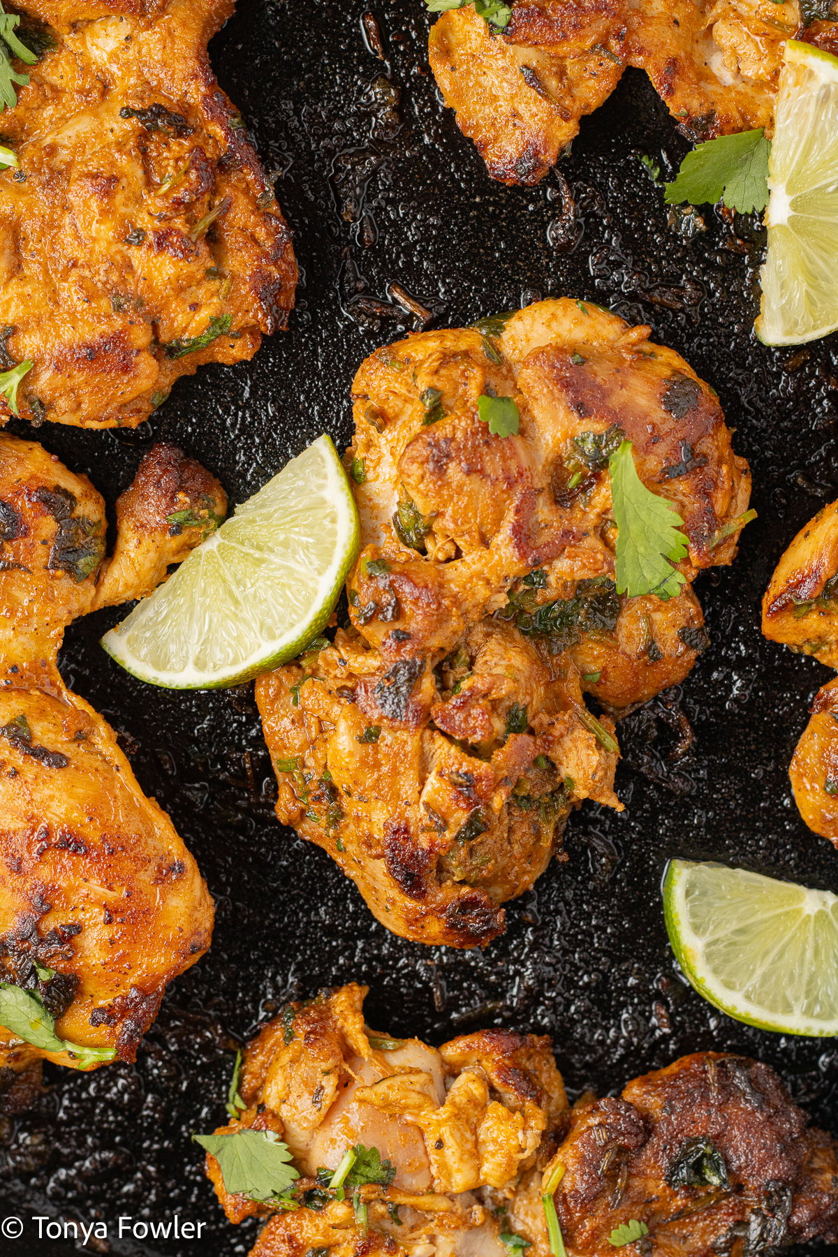 Cilantro lime chicken in a cast iron skillet with lime slices.