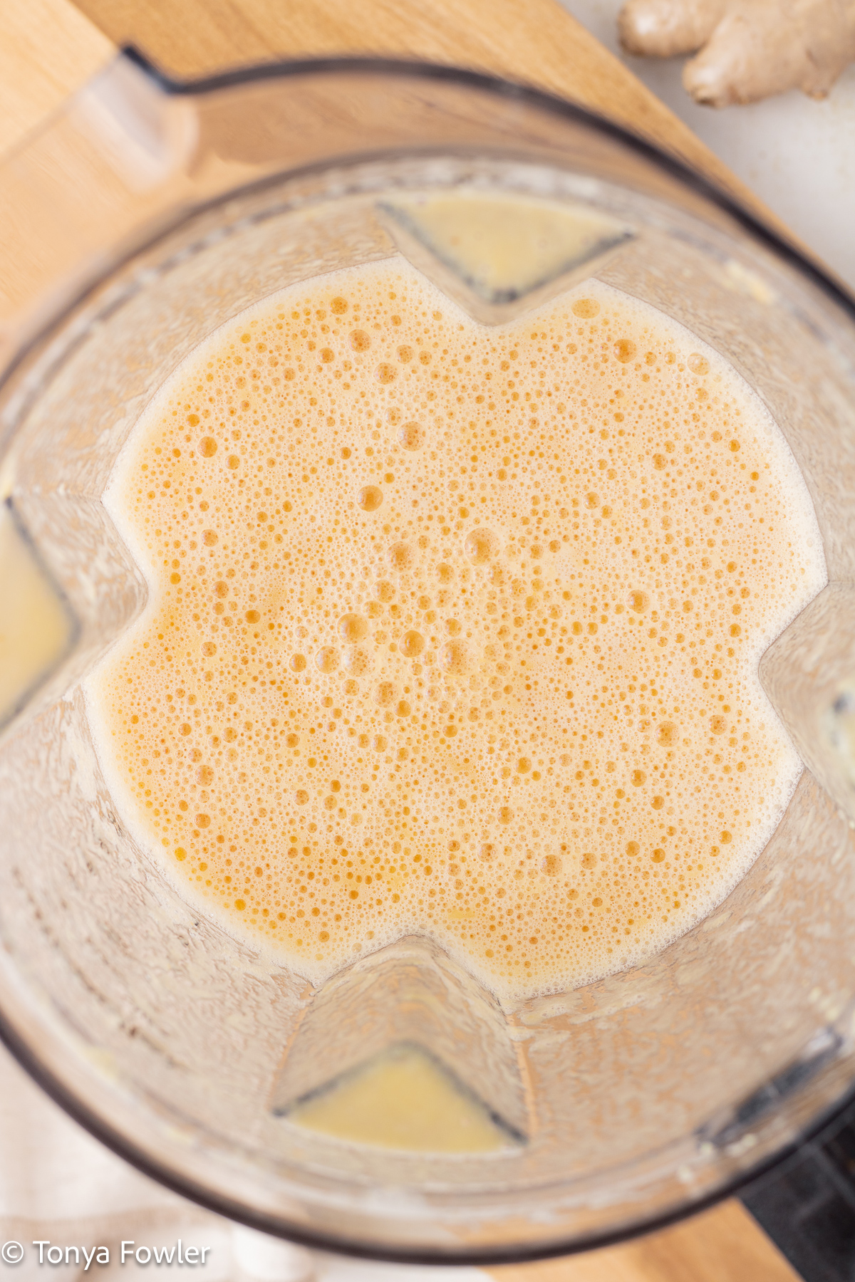 Overhead view of blended fruit and ginger in a blender.