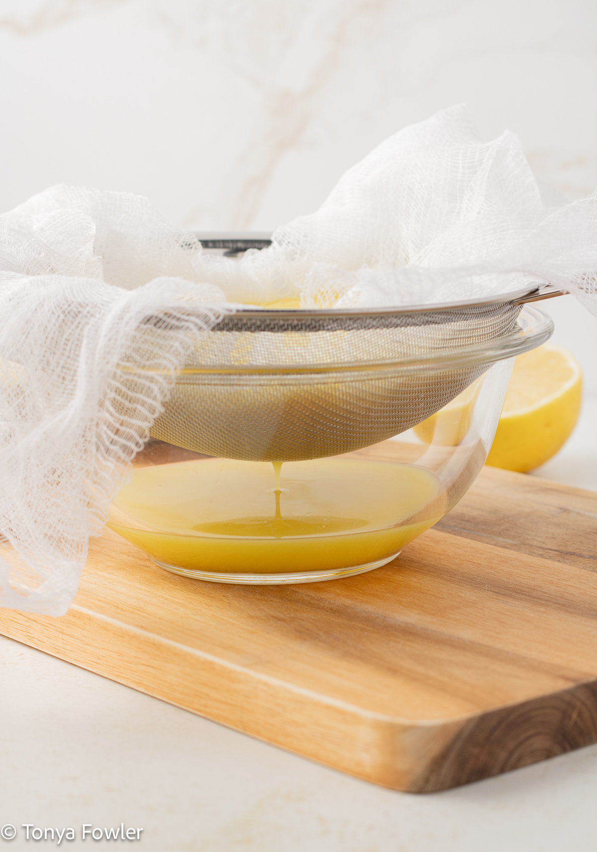 Side view of blended fruit in a fine mesh strainer over a bowl. 