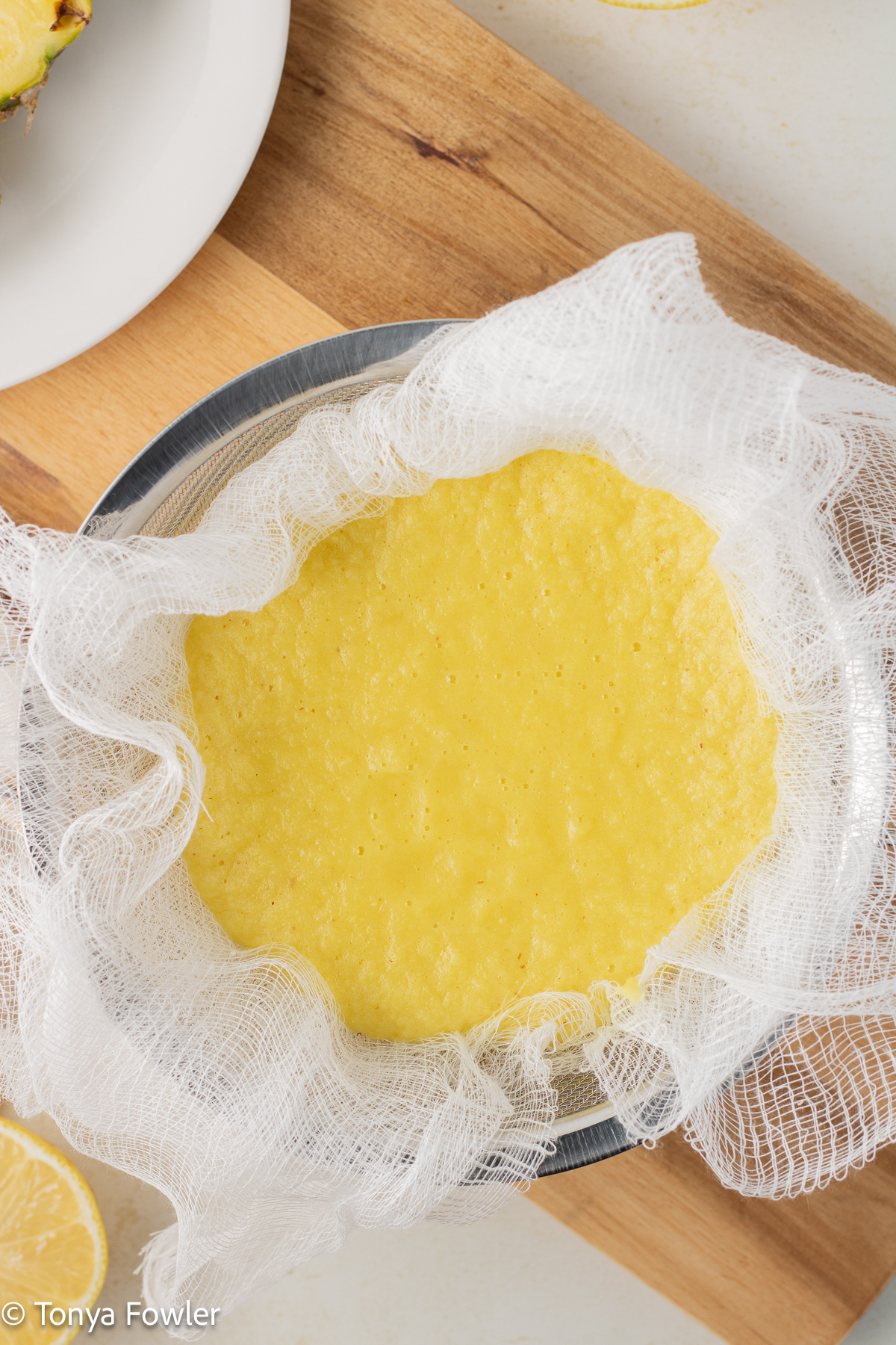 Overhead view of blended fruit in a strainer lined with cheesecloth.