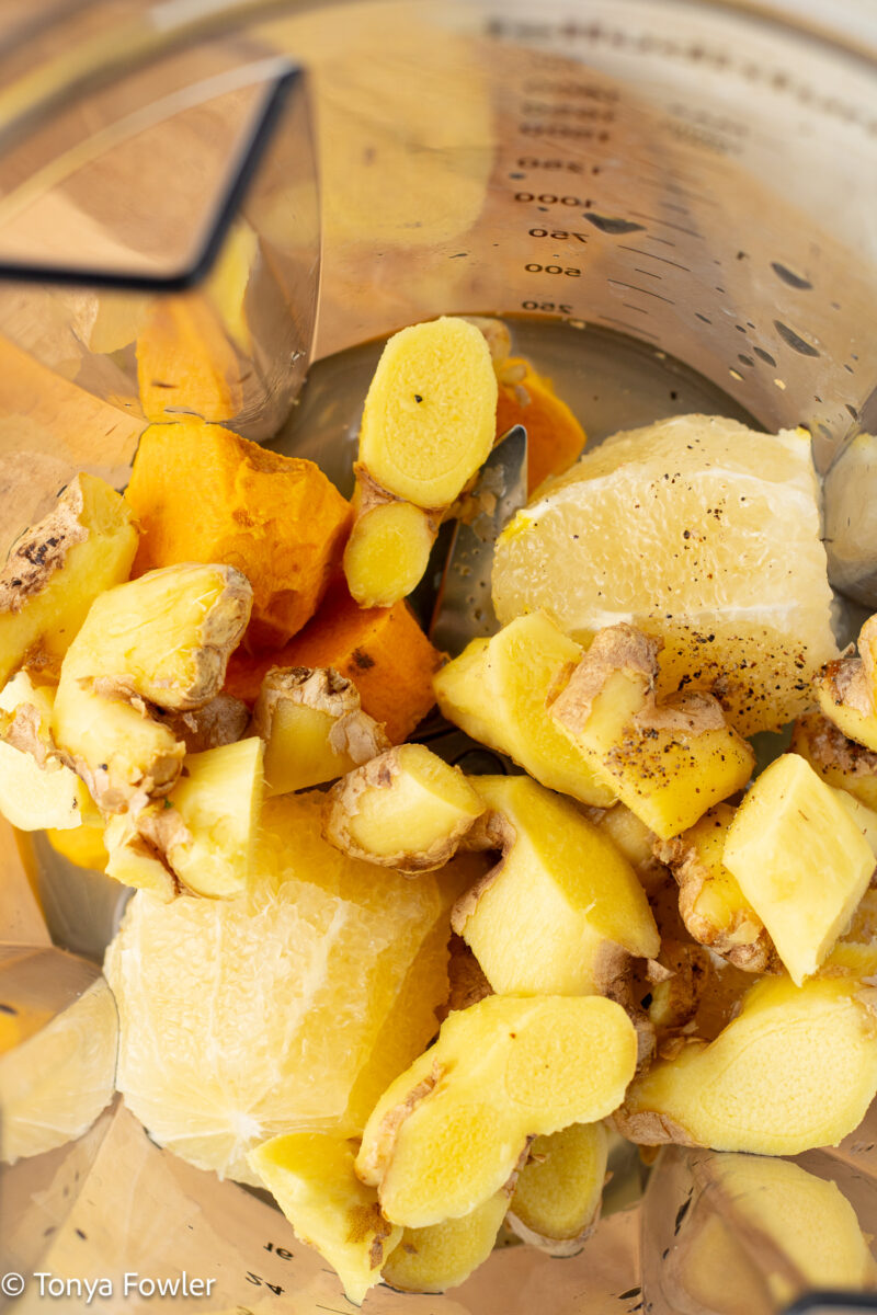 Turmeric, lemon, and ginger root in a blender.