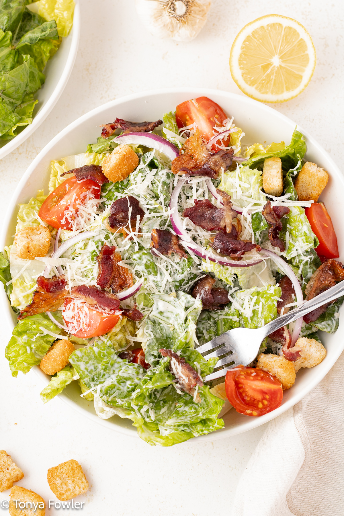 Overhead view of a caesar salad in a bowl with a fork.