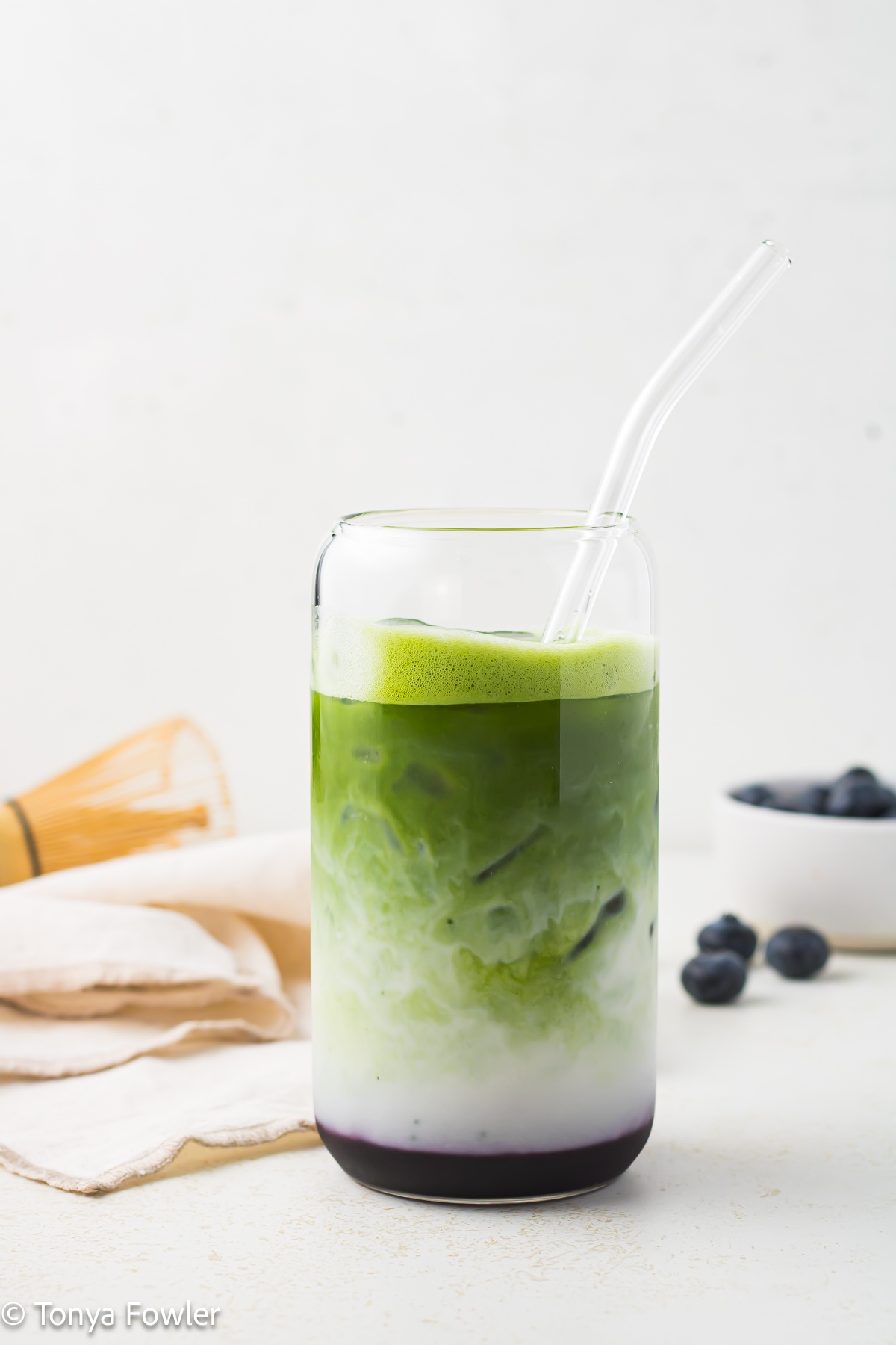Straight on view of a Blueberry Matcha Latte in a glass.