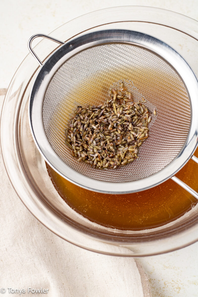 Process image of honey syrup being strained into a mixing bowl.