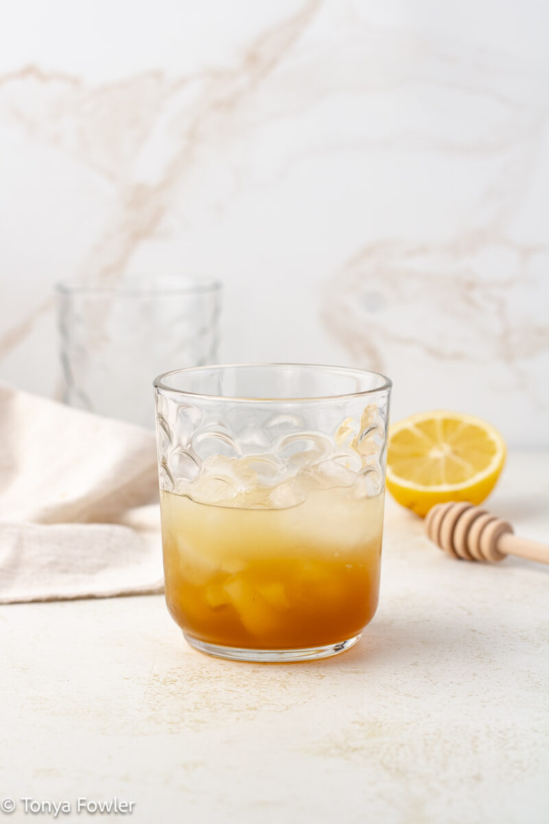 Honey syrup, lemon juice and ice in a glass. 
