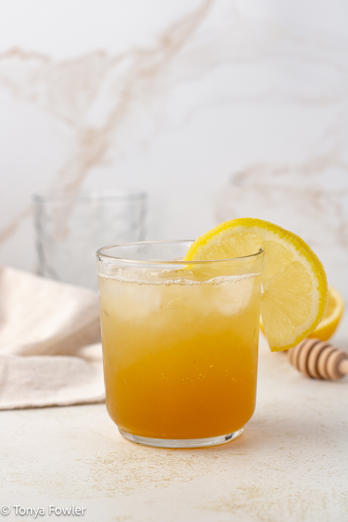 Straight on view of a drink with a lemon slice on the rim.