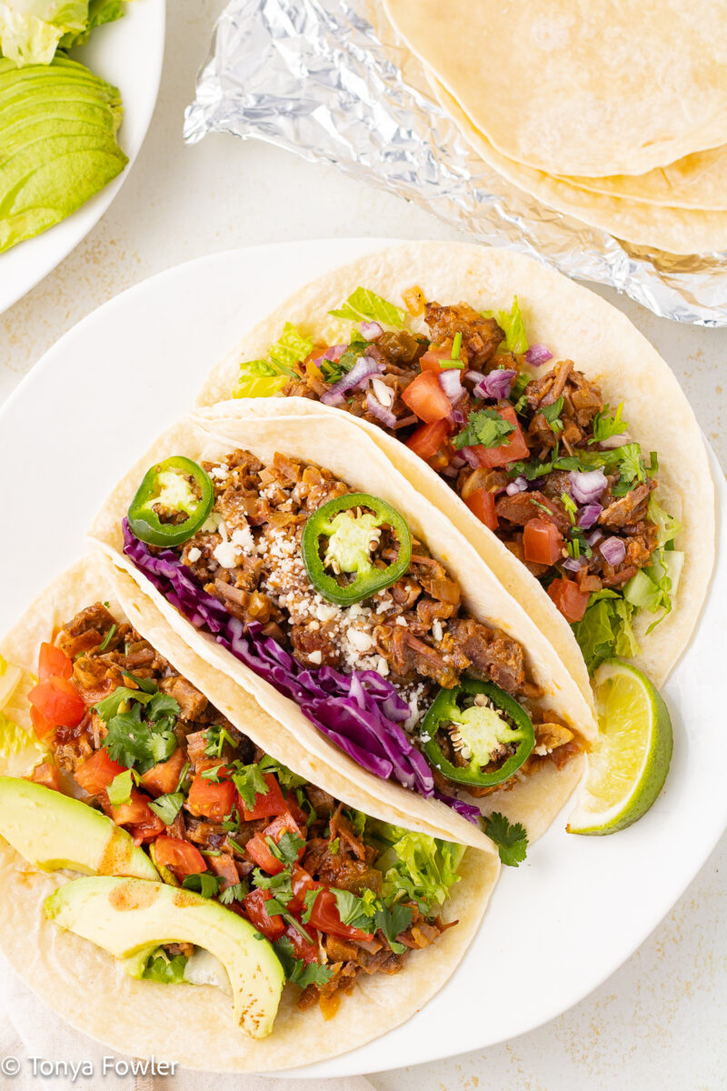 Overhead view of tacos on a plate with lime wedges.
