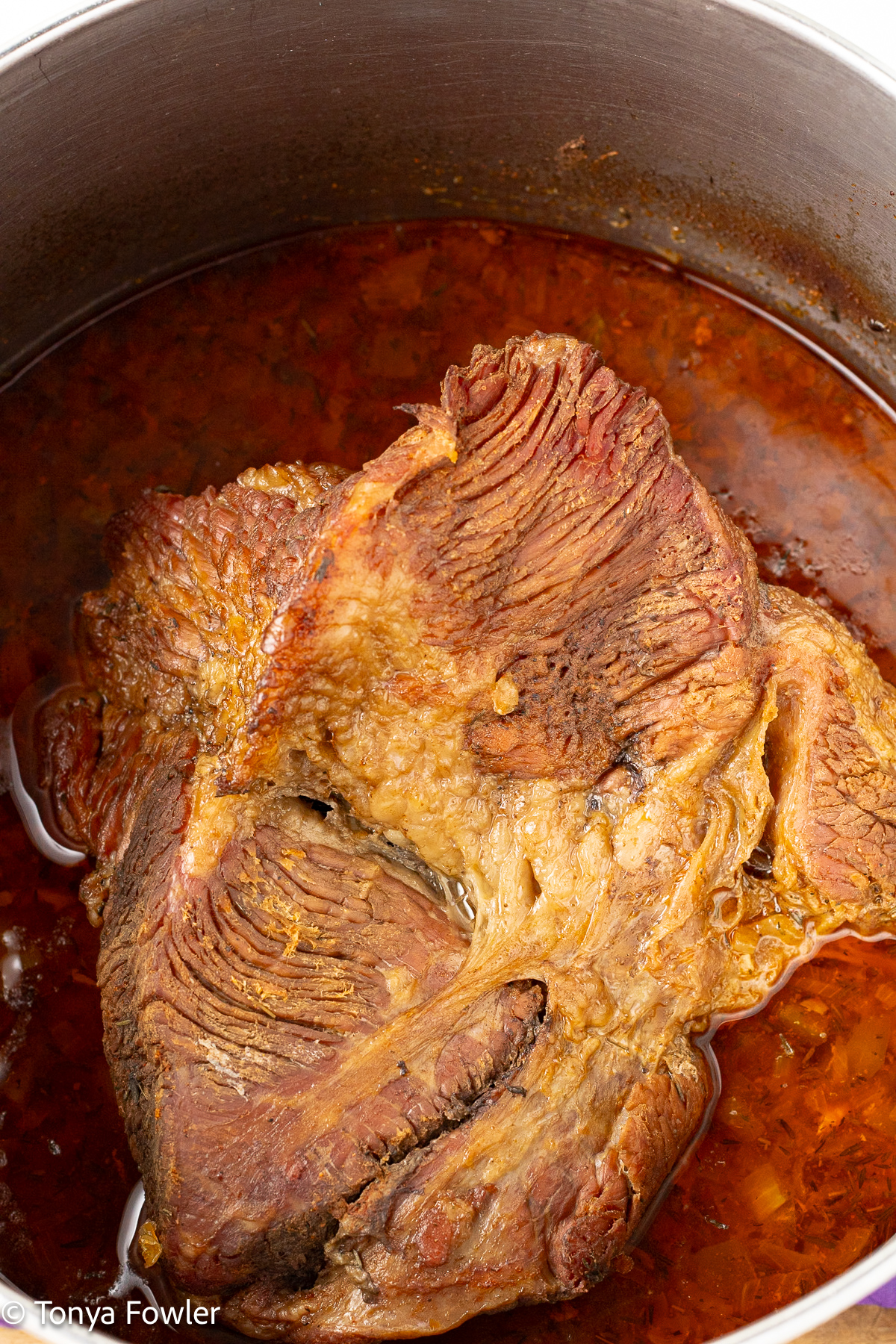 Cooked brisket in a pot with juices. 