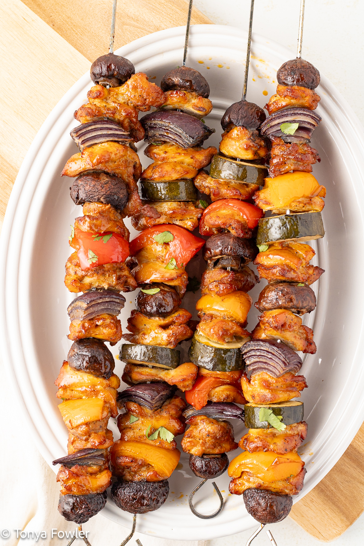 Overhead view of chicken kabobs on skewers on a platter.