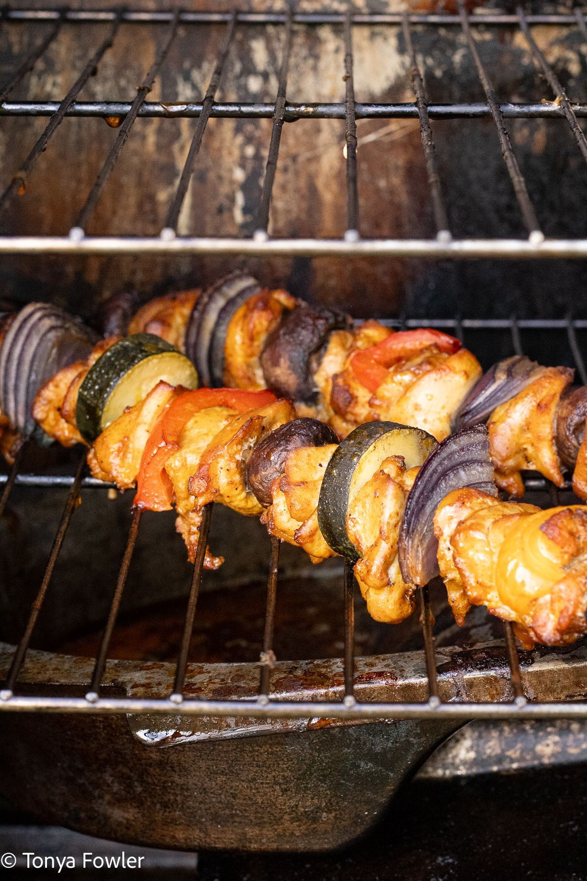 Straight on view of chicken skewers cooking inside the smoker. 
