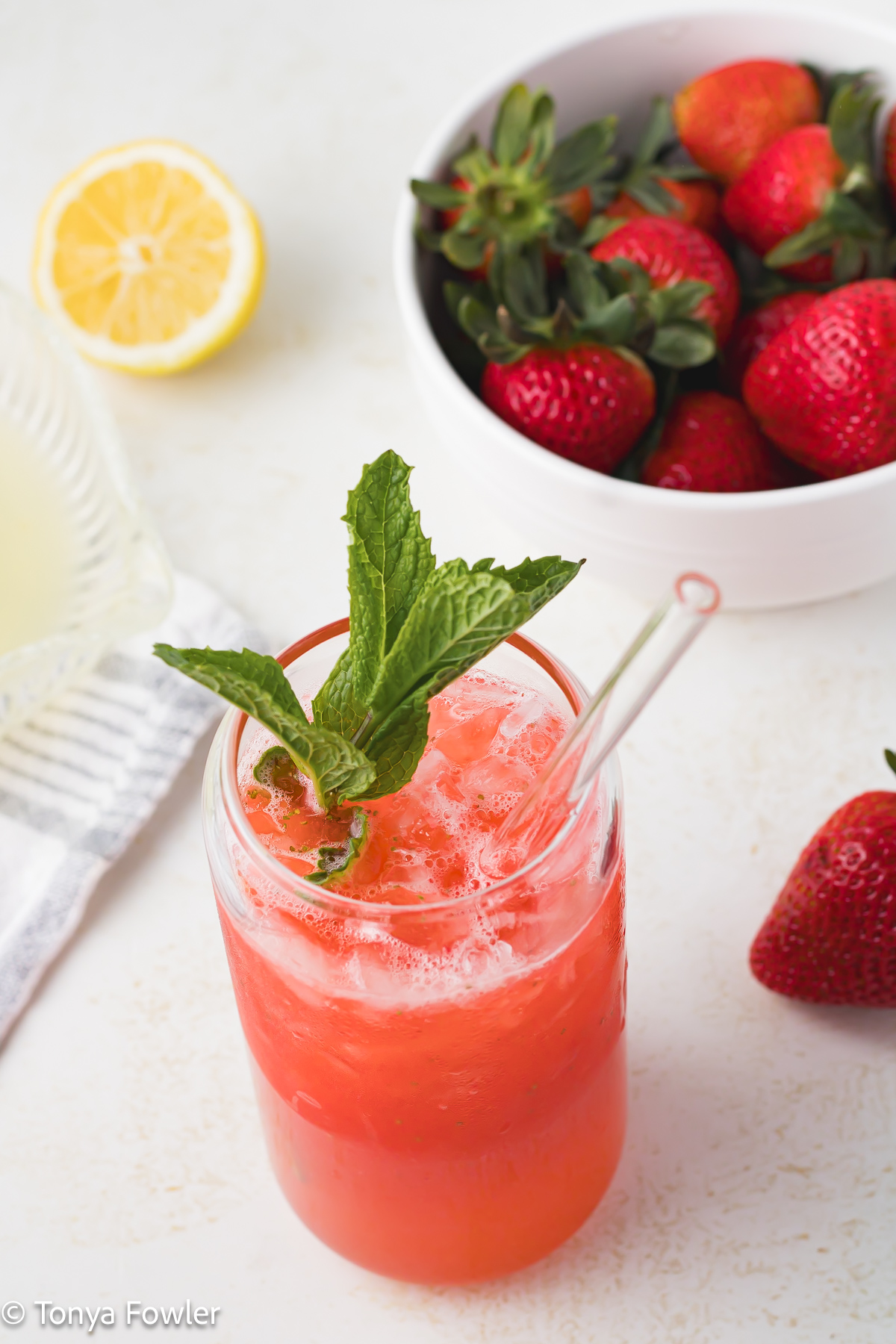 3/4 view of strawberry lemonade in a glass topped with mint. 