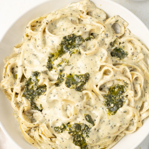 Alfredo basil pesto pasta in a bowl topped with pesto.