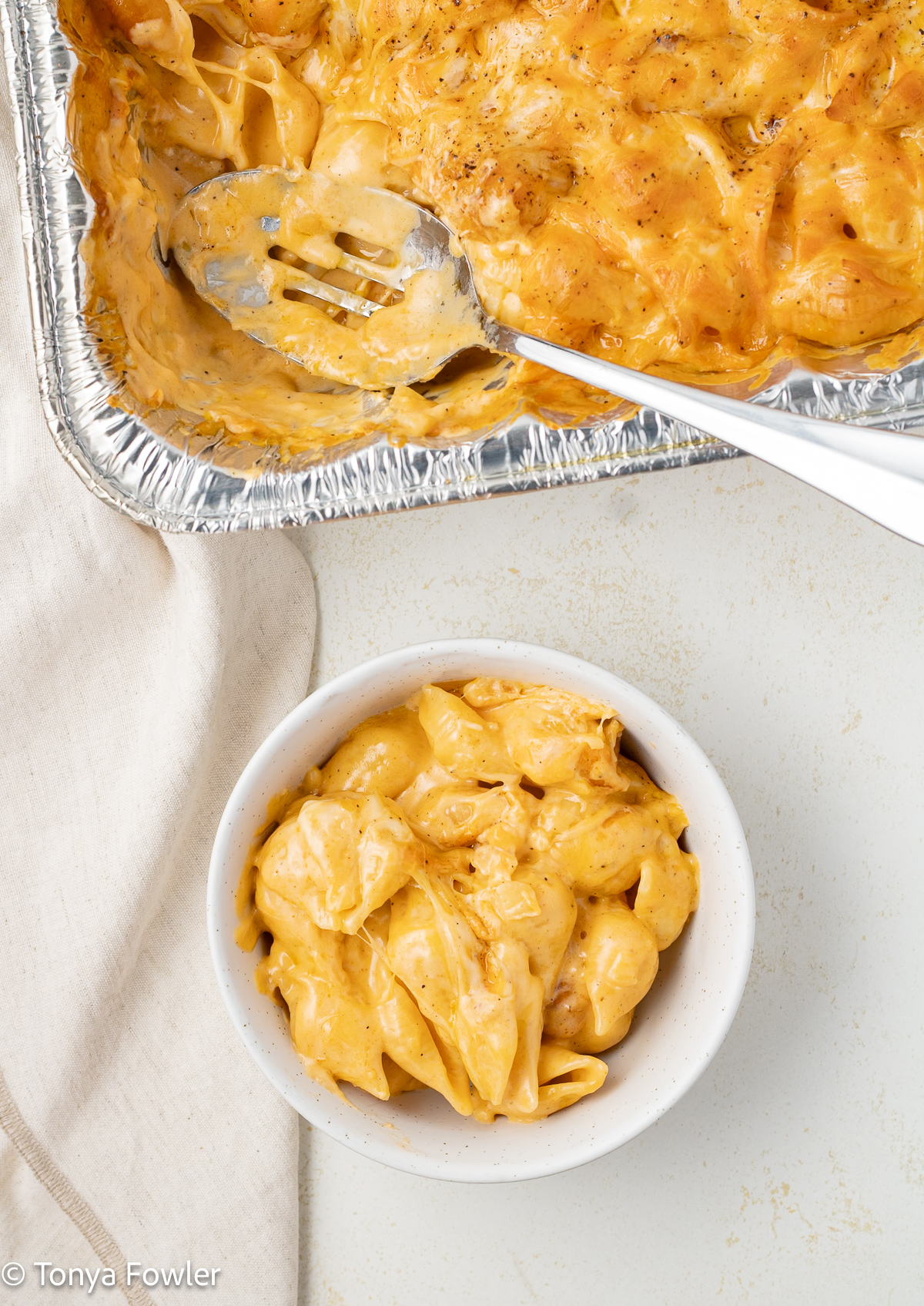 Overhead view of mac and cheese in a bowl with a pan of mac and cheese near by.