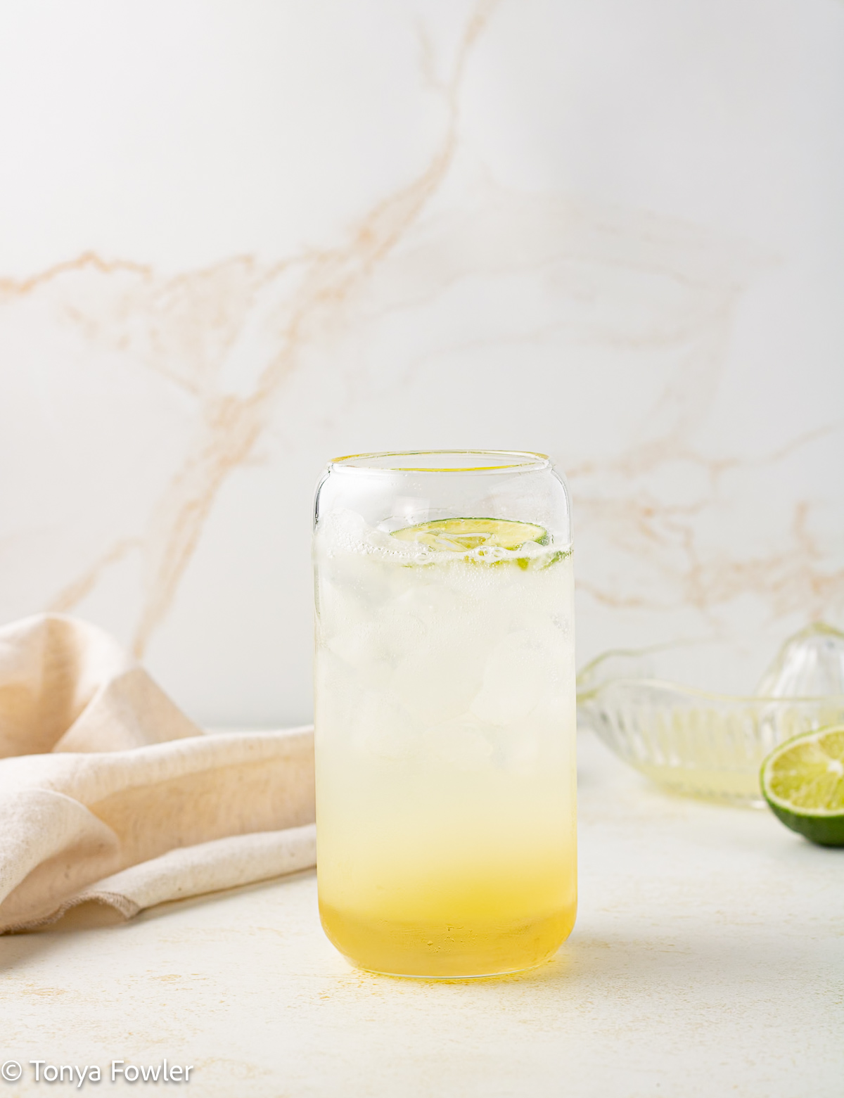 Straight on view of a glass filled with ice, sparkling water and syrup.
