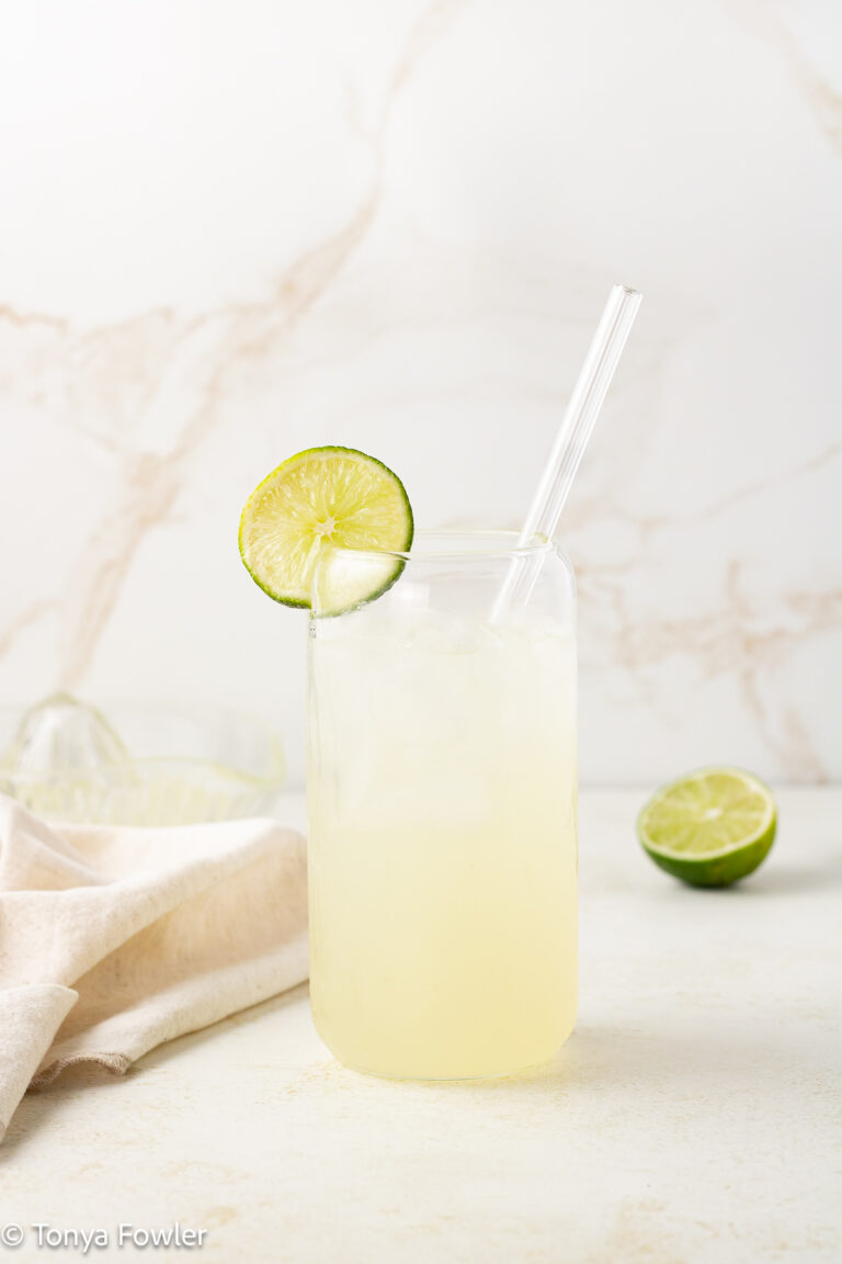 Straight on view of a sparkling drink with a slice of lime on the rim.