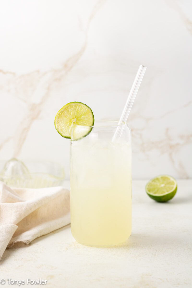 Straight on view of a sparkling drink with a slice of lime on the rim.