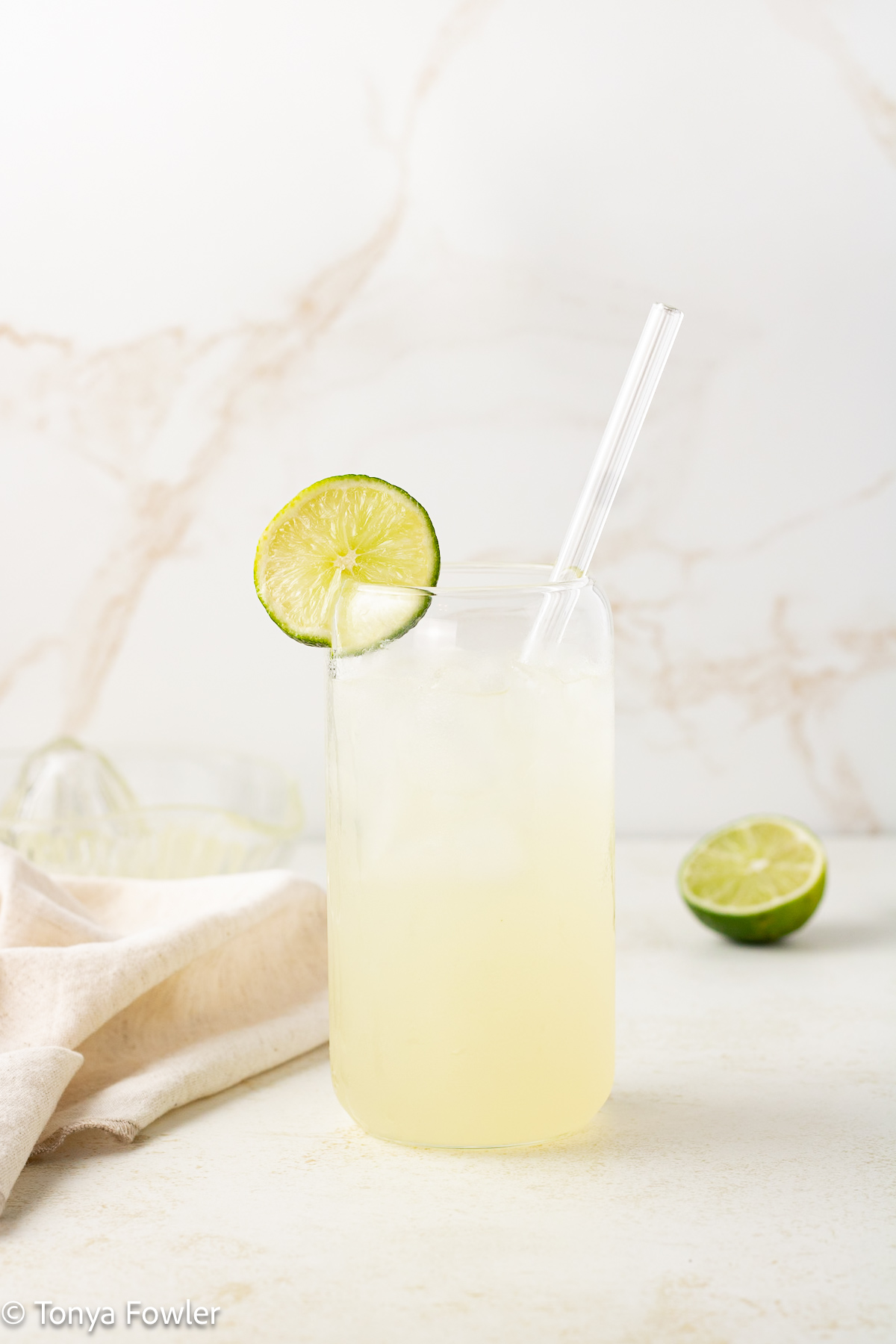 Straight on view of a sparkling drink with a slice of lime on the rim.
