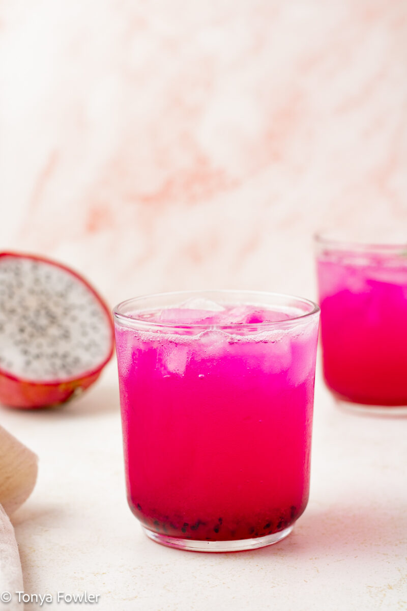 Straight on view of a sparkling mocktail with dragon fruit in the background.