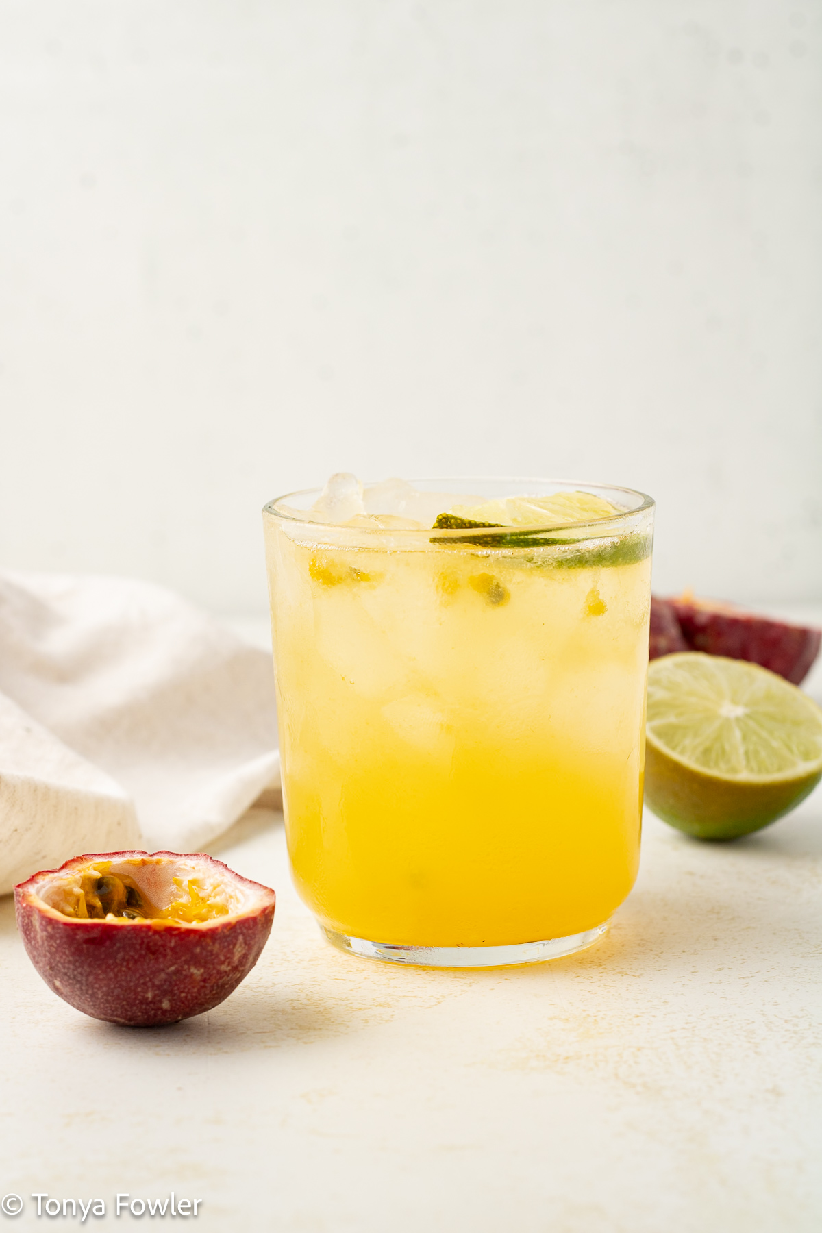 A straight on view of a fruit mocktail with fresh passionfruit and lime.