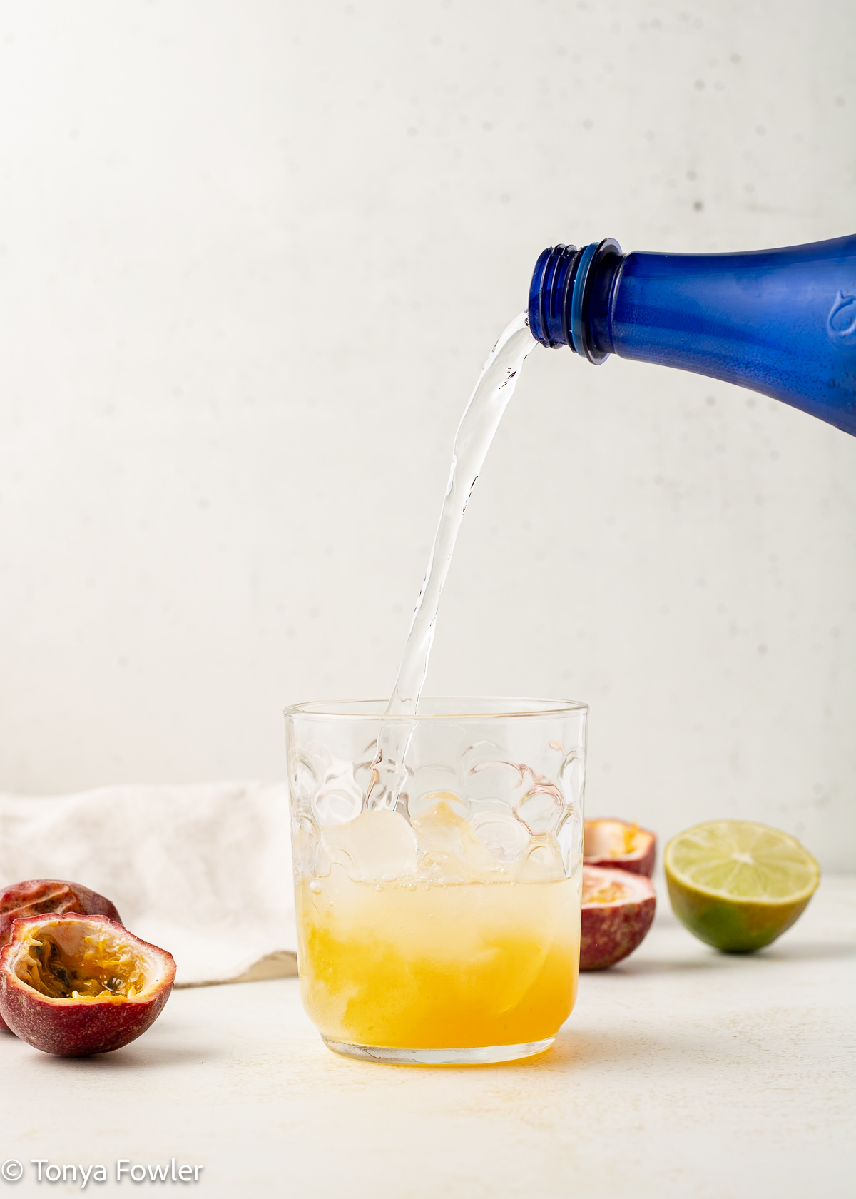 Sparkling water being poured into a glass with syrup.