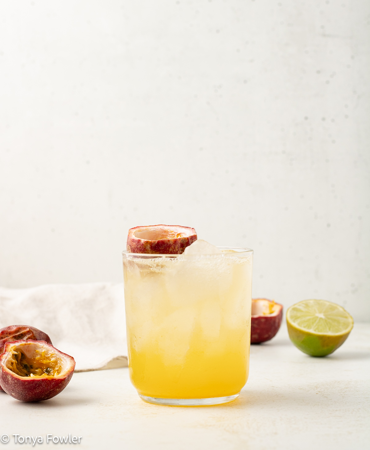 Passionfruit mocktail in a glass with fresh passionfruit and lime.
