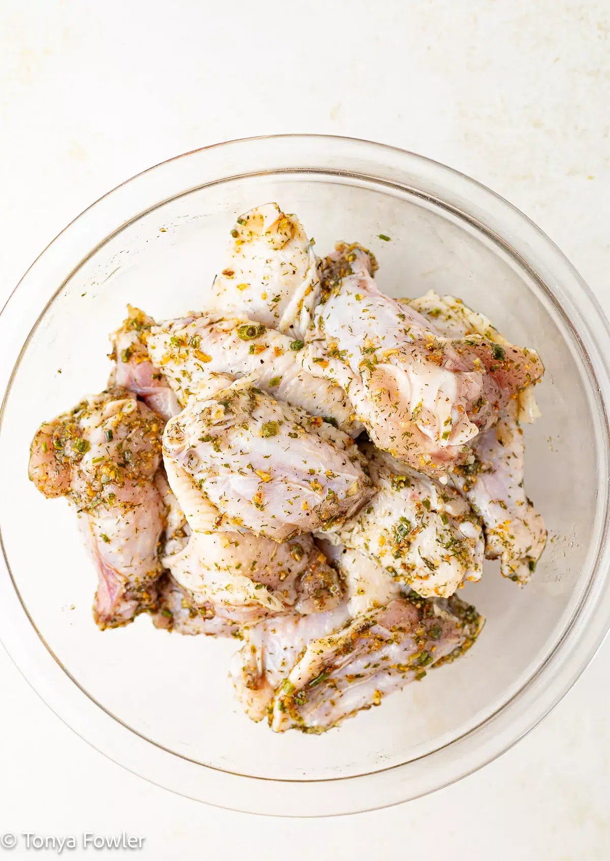 Raw chicken wings coated in herbs.