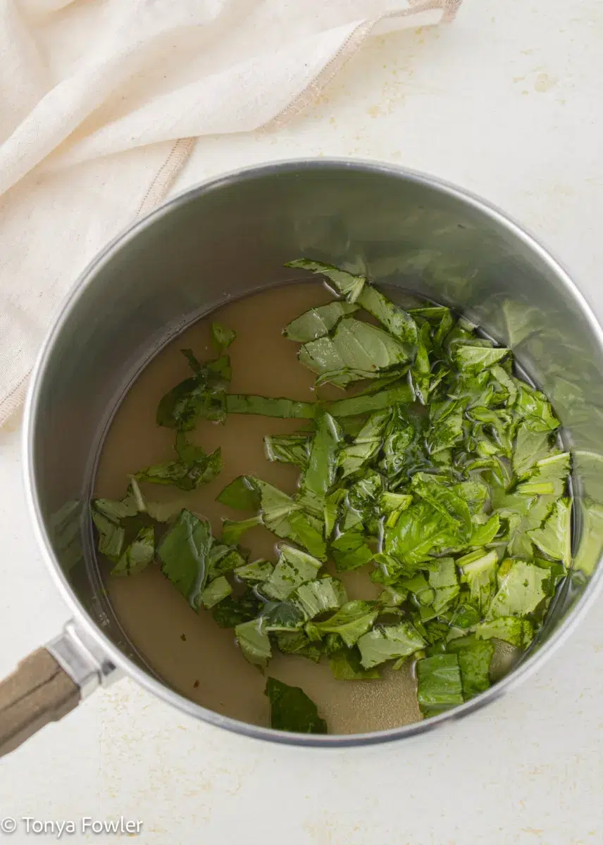 Sugar, water and chopped basil in a pot. 