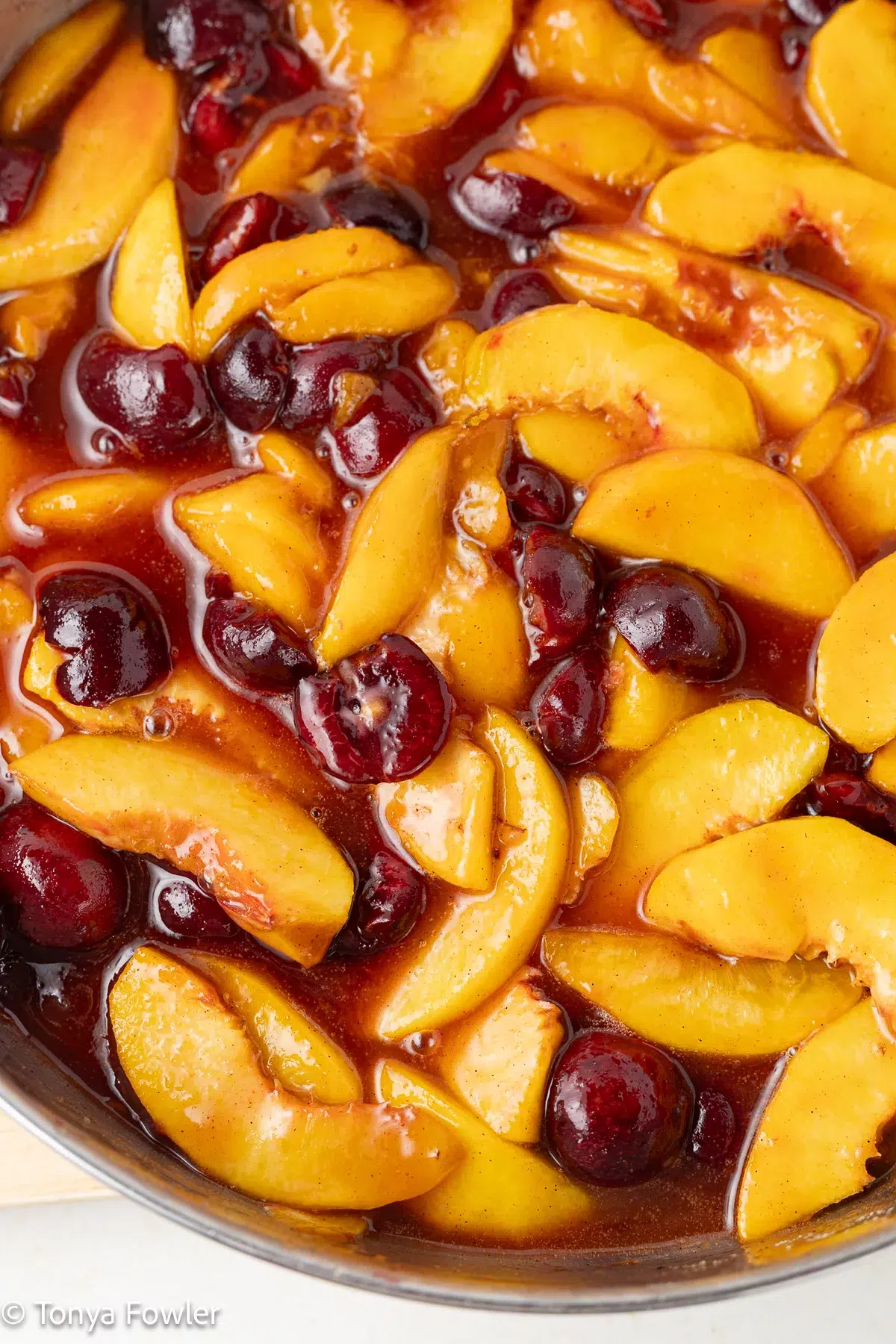 Cooked cherries and peaches in a skillet.