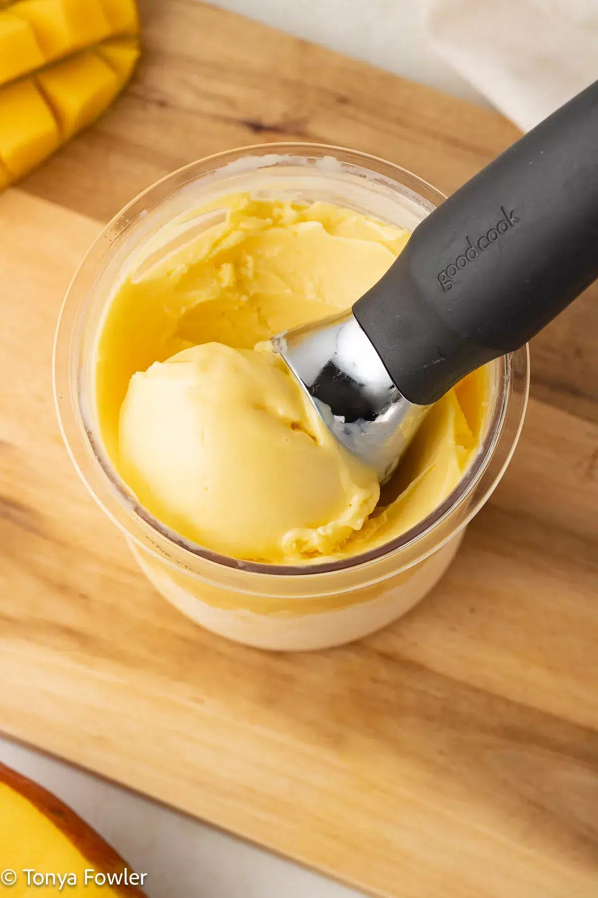 A scoop of frozen yogurt in a pint container with an ice cream scoop.