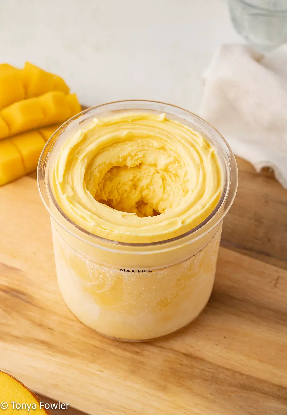 Blended mango frozen yogurt in a pint container.