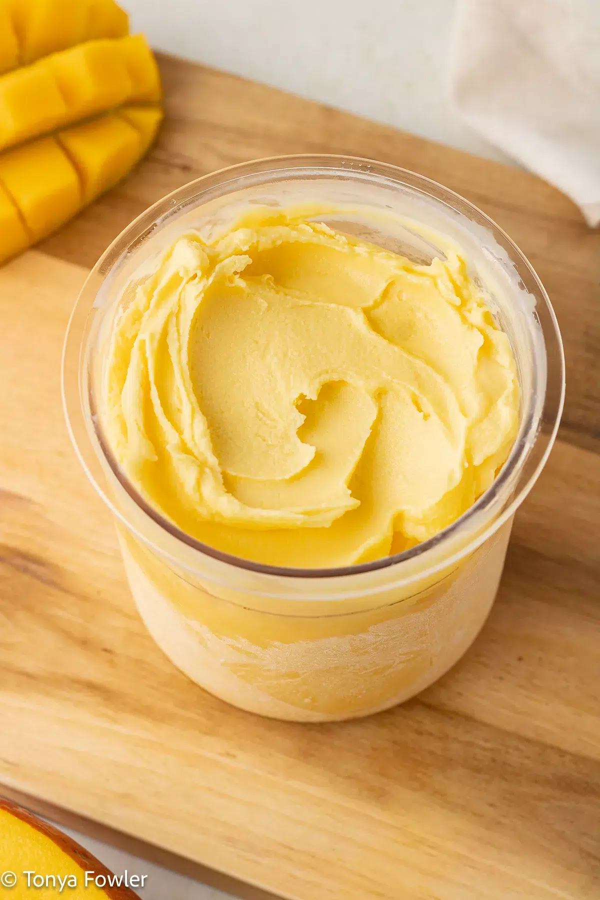 3/4 image of mango frozen yogurt in a pint container.