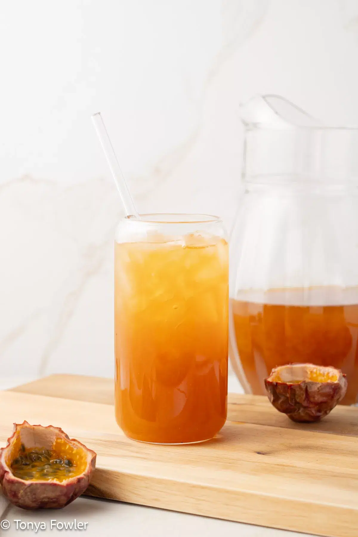 Passionfruit tea in a glass with fresh passionfruit near by.