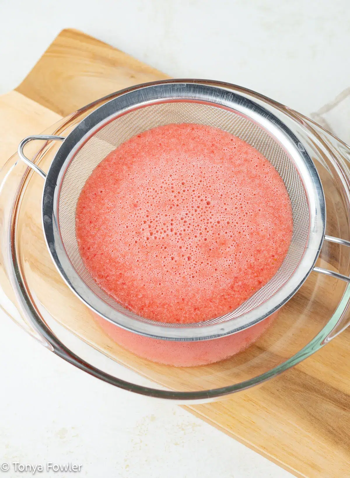 Fruit puree being strained into a bowl.