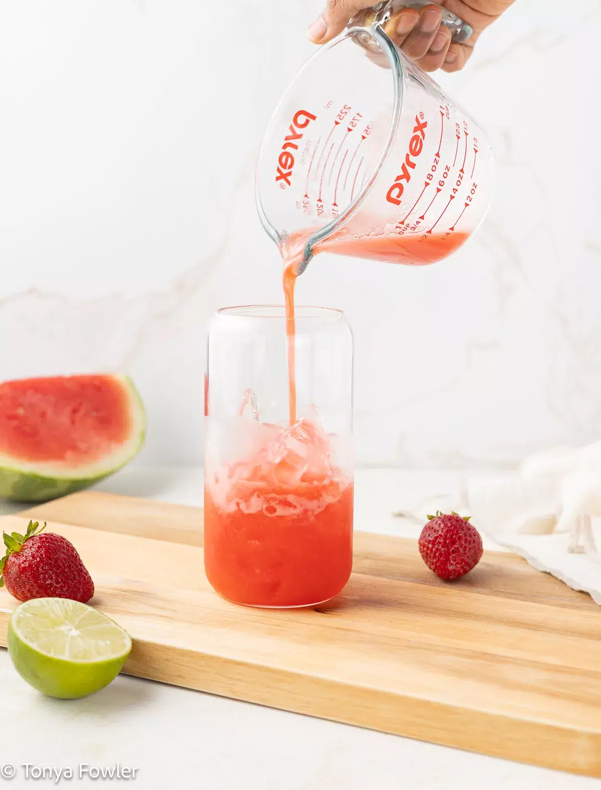 Fruit juice being poured into a cup with ice.