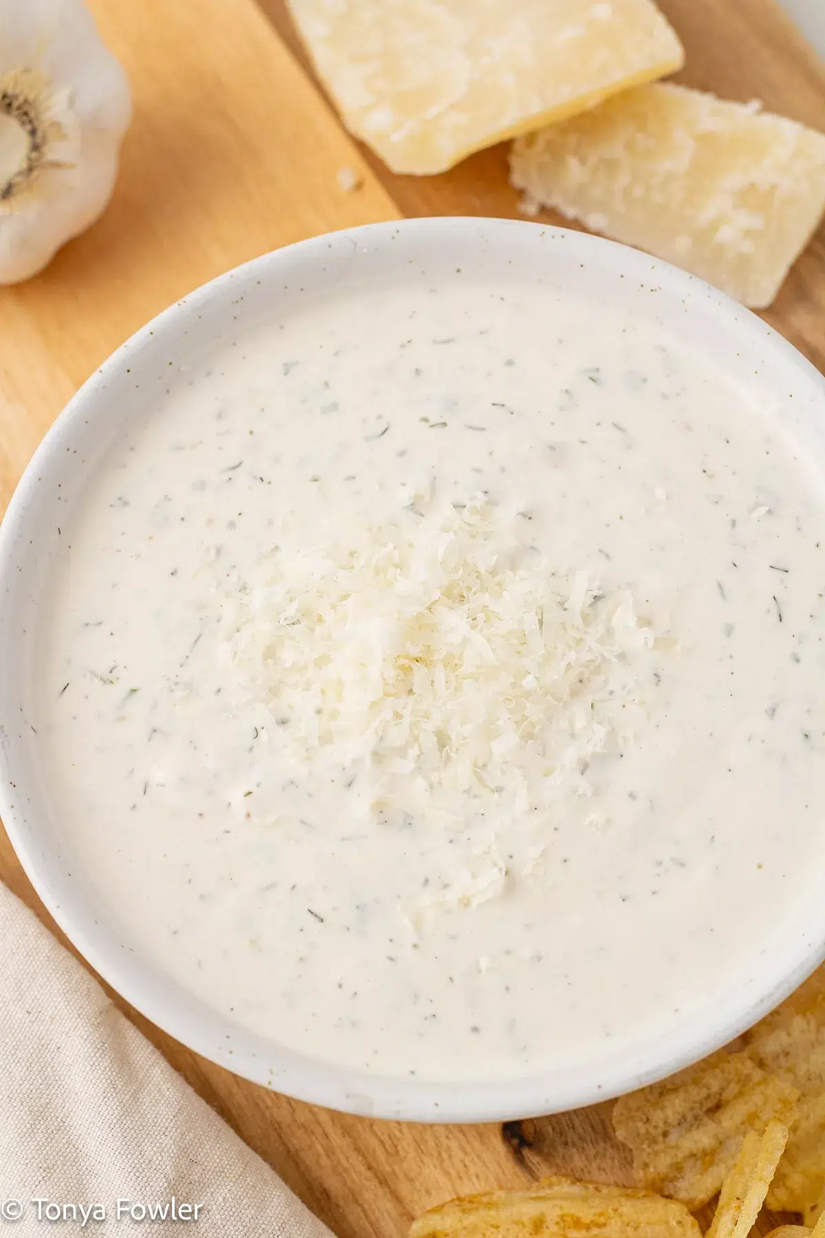 Close up image of ranch dressing in a bowl topped with parmesan cheese.