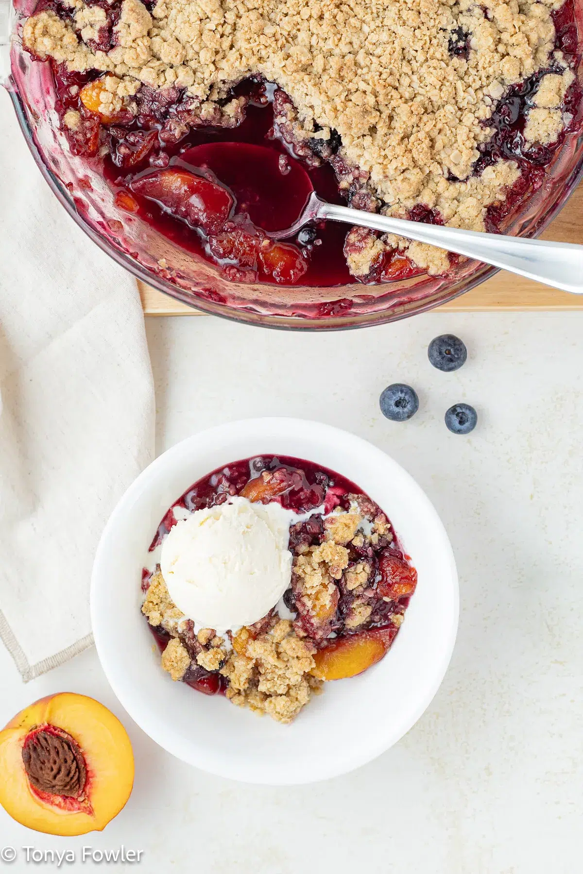 Overhead image of gluten free peach crisp in a pie dish and in a bowl with a scoop of ice cream.