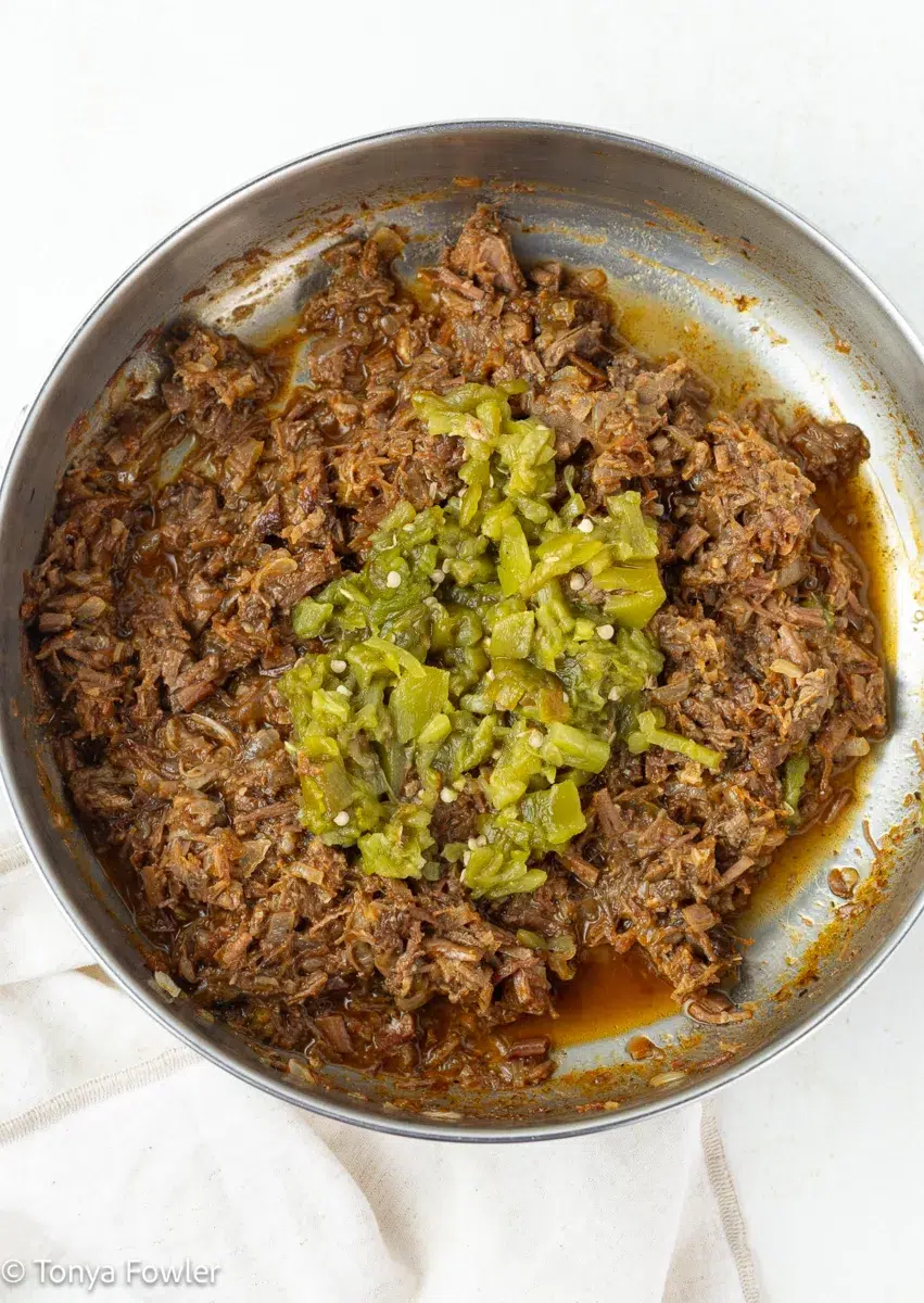 Chopped meat in a skillet with chiles.