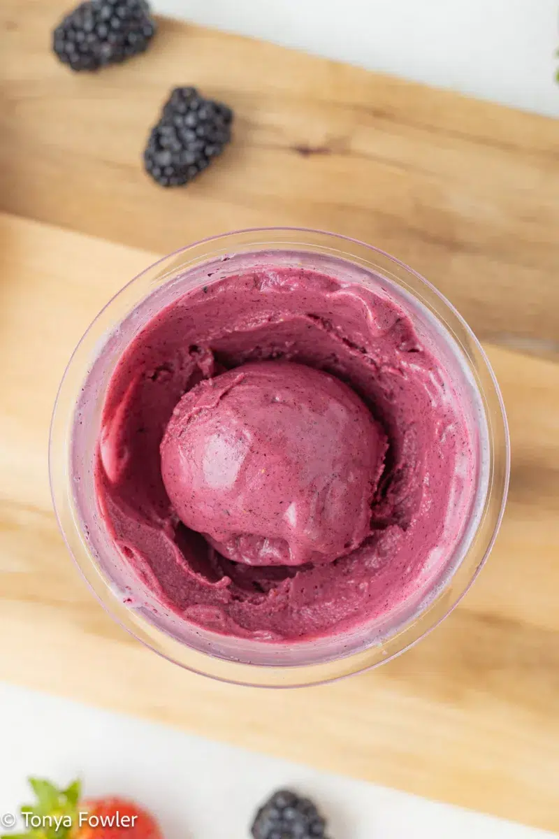 A scoop of Ninja creami mixed berry frozen yogurt in a pint container.