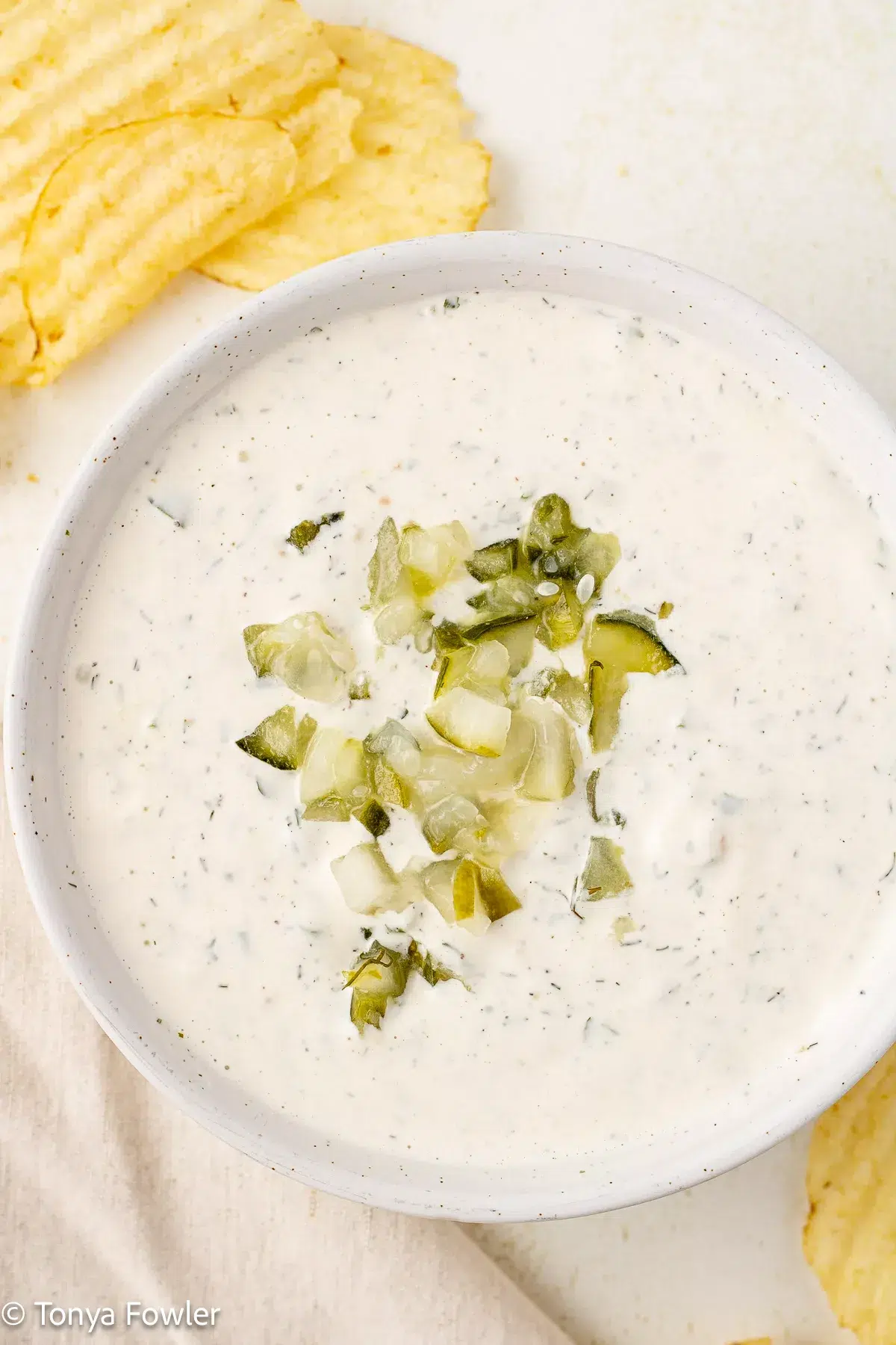 Dill pickle ranch in a bowl topped with chopped pickles.